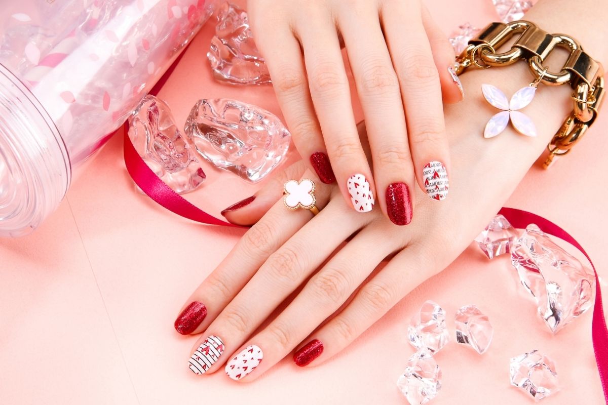 Unghie natalizie con base bianca e strisce diagonali rosse e verdi in stile caramella natalizia