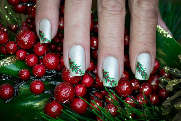 Unghie natalizie semplici color argento con decorazioni di rami di agrifoglio verdi e rossi
