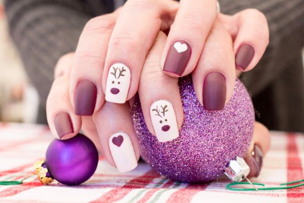 Unghie natalizie con base opaca color prugna e decorazioni bianche con viso di renna e cuore