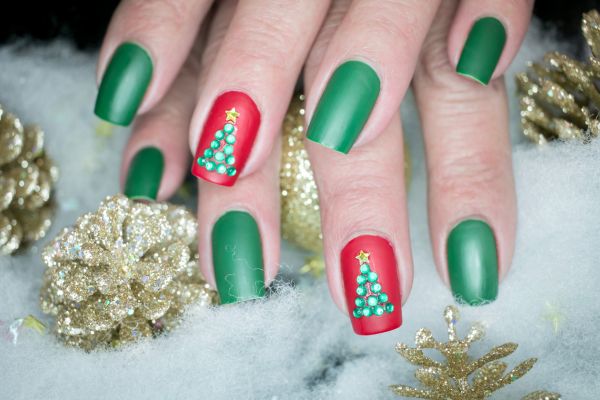 Unghie di Natale verdi e rosse con decorazioni a forma di albero di Natale realizzate con pietre brillanti